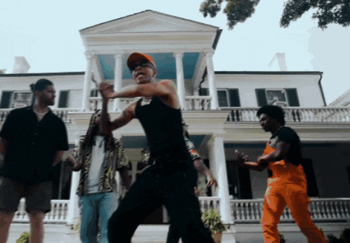 a group of men are dancing in front of a large white house