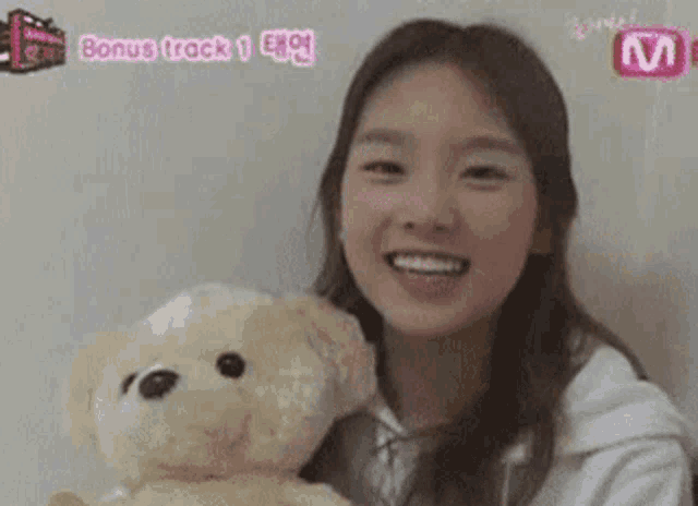 a young woman is smiling while holding a teddy bear .