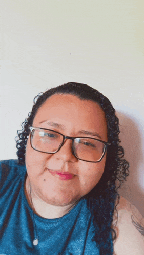 a woman wearing glasses and a blue shirt is smiling for the camera