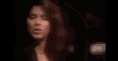 a woman is singing into a microphone in a dark room in a blurry photo .