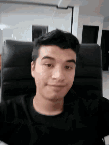 a man in a black shirt is sitting in a black chair