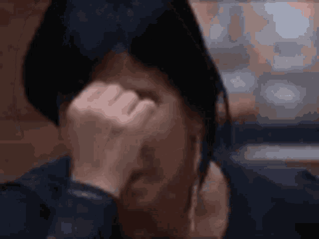 a close up of a woman covering her face with her hand .