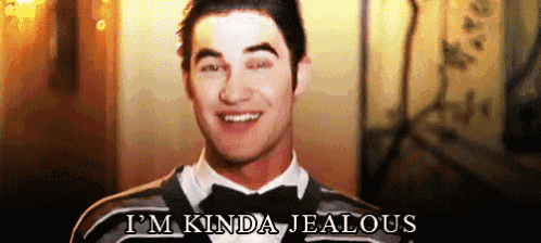 a man in a tuxedo and sweater is smiling and saying `` i 'm kinda jealous '' .