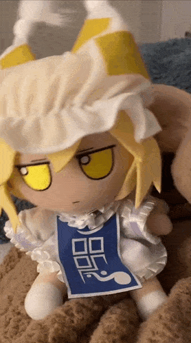 a stuffed doll with yellow eyes is sitting on a couch .
