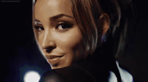 a woman with a nose ring is smiling and looking over her shoulder .