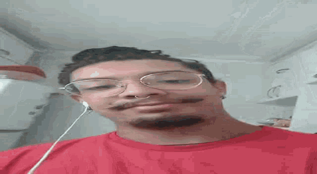 a man with a beard and glasses is wearing headphones and a red t-shirt .