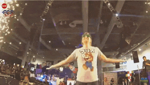 a man wearing a mario shirt is dancing in a room with a coca cola logo on the ceiling