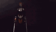 a woman in a black and orange dress is holding a sword .