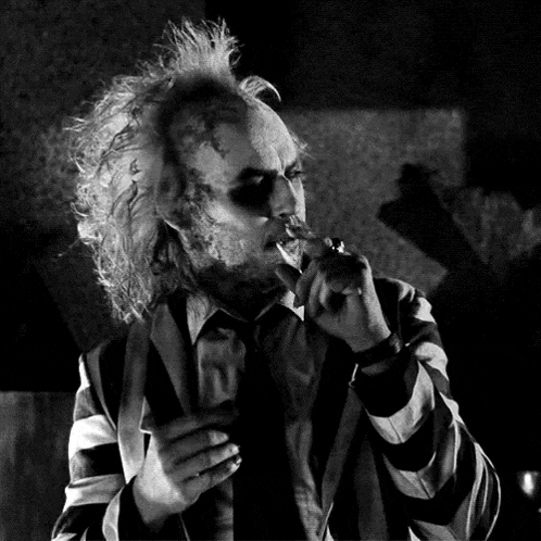 a man in a striped suit is smoking a cigarette in a black and white photo .