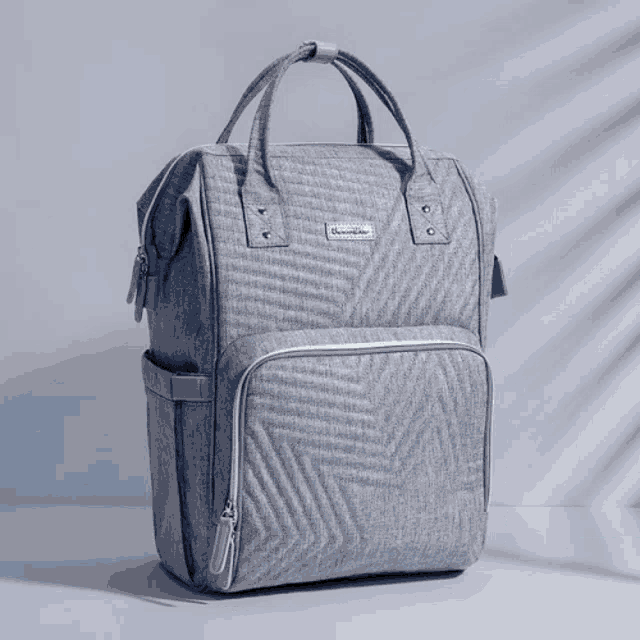 a blue diaper bag with a chevron pattern sits on a white surface