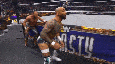 two men are wrestling in a ring with a banner that says new castle on it