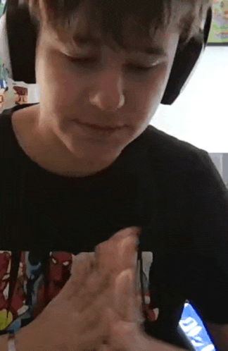 a young boy wearing headphones is playing a video game on a tablet .