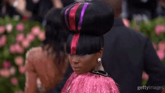 a woman wearing a pink dress and a large bun in her hair .
