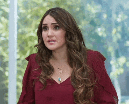 a woman wearing a red top and a necklace with the letter m on it