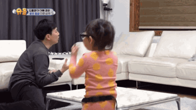 a man kneeling down next to a little girl in a living room with a sign that says ' a ' on it