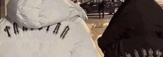 a person wearing a black jacket and a white jacket with a hood is walking down the street .