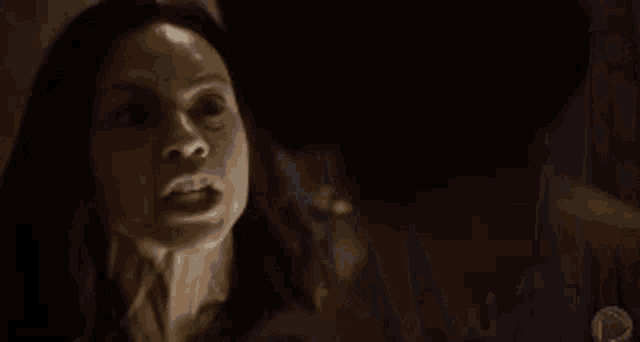two women are standing next to each other in a dark room looking at each other .