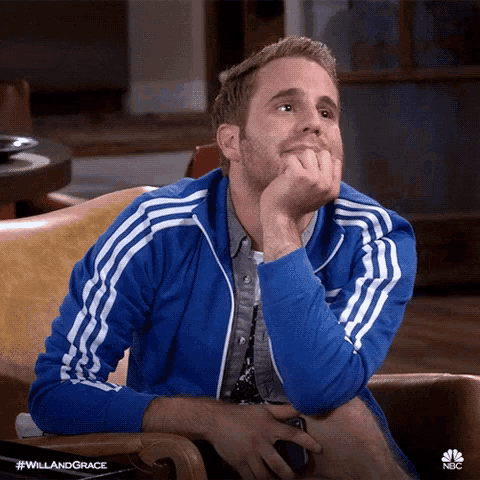 a man in a blue adidas jacket sits in a chair with his hand on his chin