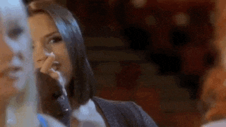 a woman is crying while talking on a cell phone in front of a group of people .