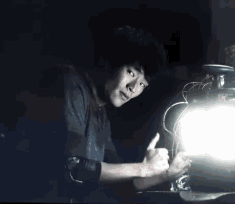 a man giving a thumbs up in the dark