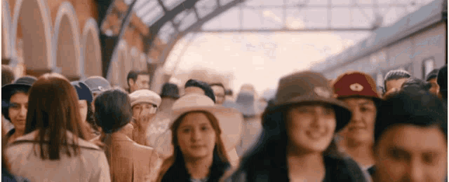 a crowd of people wearing hats are walking down a train platform