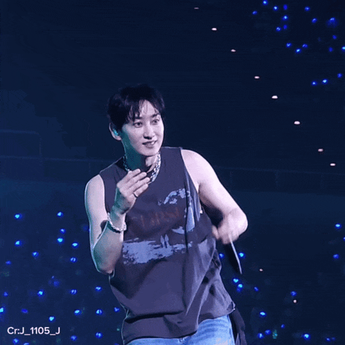 a man in a black tank top stands on a stage with crj_1105_j in the corner