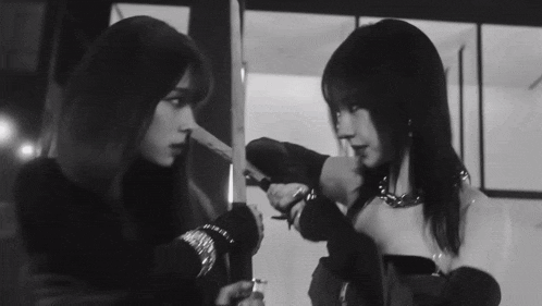a black and white photo of two women standing next to each other looking at each other .