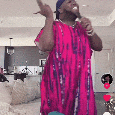 a man in a pink tie dye shirt singing into a microphone