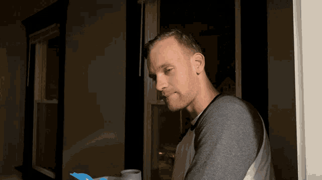 a man standing in front of a window with a blue object in his hand