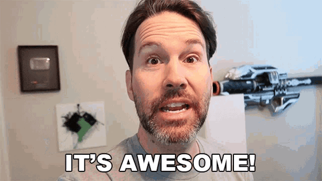 a man with a beard says " it 's awesome " in front of a gun