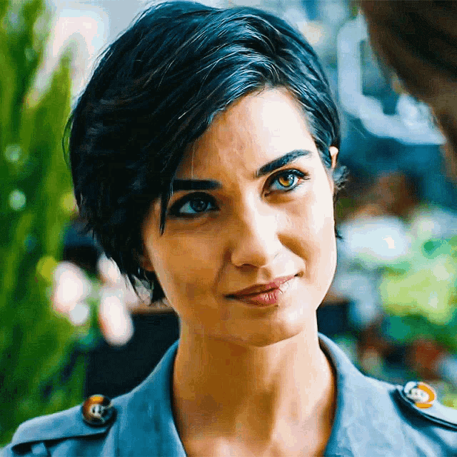 a woman with blue hair and green eyes is smiling