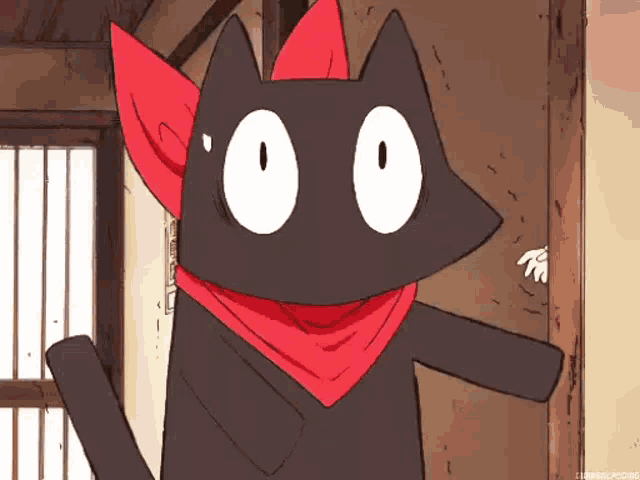a black cat wearing a red scarf around its neck is standing in a room .