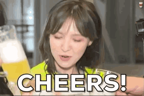 a woman is holding a glass of beer and making a cheers gesture .