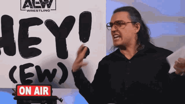 a man in front of a sign that says hey on air
