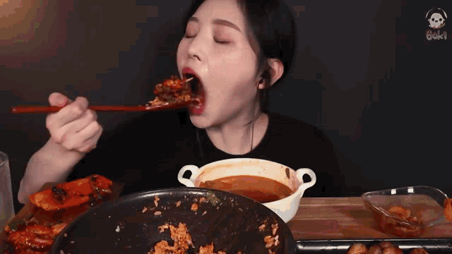 a woman is eating a meal with chopsticks and a bowl of soup