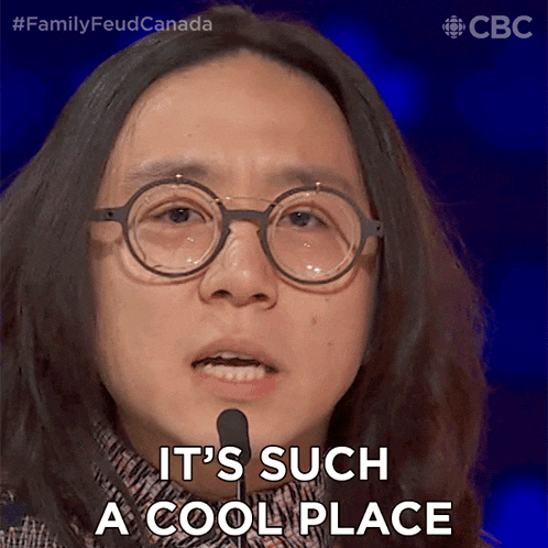 a woman wearing glasses says it 's such a cool place in front of a microphone