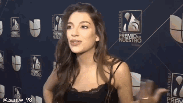 a woman standing in front of a premio lo nuestro logo
