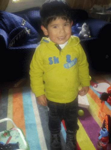 a young boy wearing a yellow sweater with the letters sk on the front