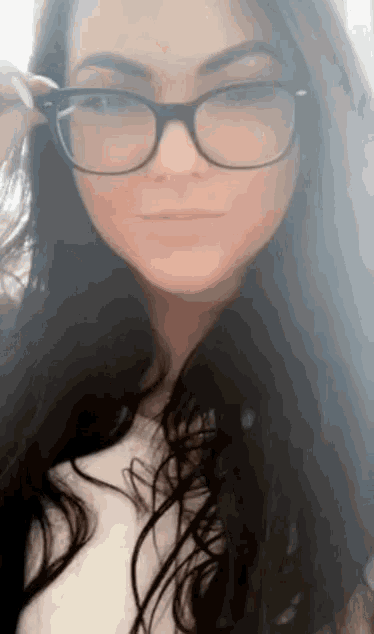 a woman wearing glasses and a white shirt is smiling