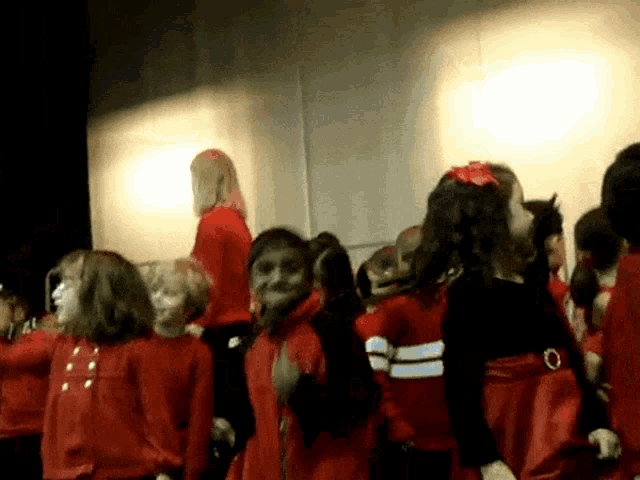 a group of young girls in red dresses are dancing