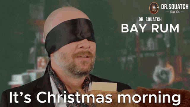 a man is blindfolded and holding a piece of paper with the words it 's christmas morning on it