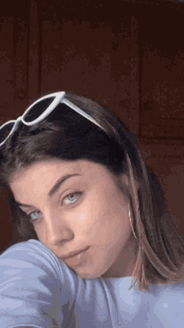 a woman wearing sunglasses is taking a selfie with her hand on her shoulder