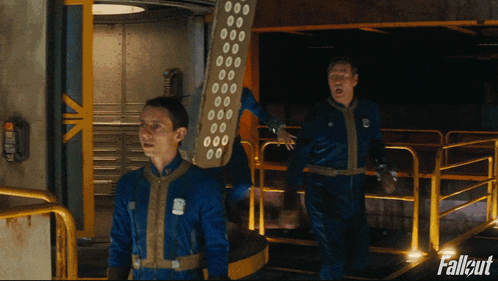 two men in blue jumpsuits are walking in a hallway with fallout written on the bottom