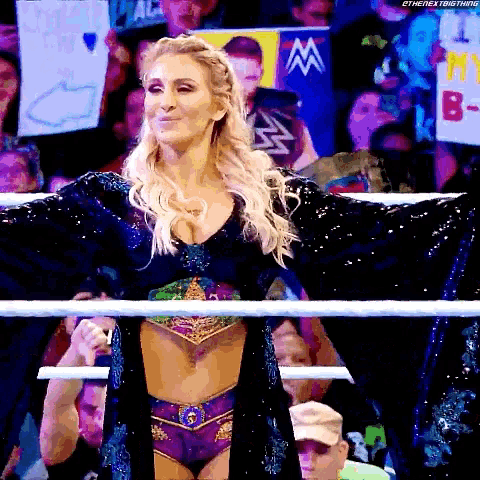a woman is standing in a ring with her arms outstretched in front of a crowd .