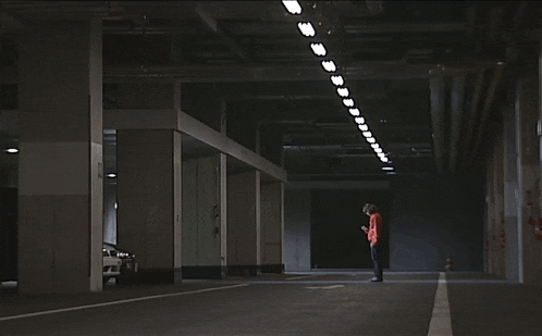 a person kneeling in a dark parking garage