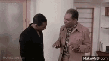 two men are standing next to each other in a room .