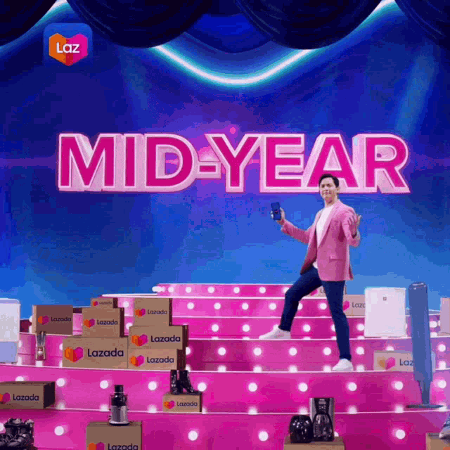 a man in a pink suit stands on a stage with the words mid-year