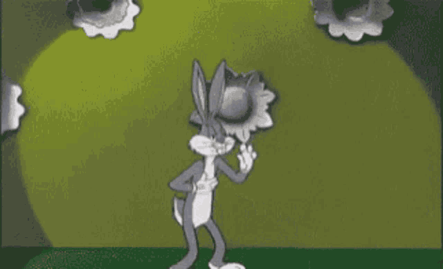 bugs bunny is standing in front of a green background holding a flower in his hand .
