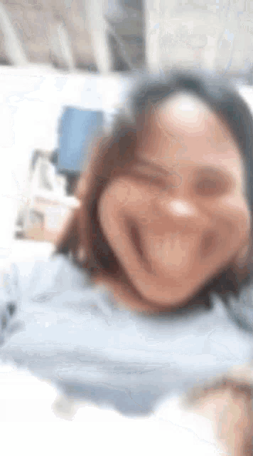 a blurry picture of a woman making a funny face while taking a selfie .
