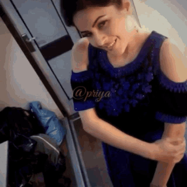 a woman in a blue dress is standing in front of a door with the name priya written on it